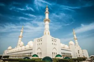 Home Stunning exterior shot of Sheikh Zayed Mosque with its iconic domes and minarets against a clear blue sky.