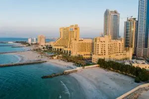 Home A stunning aerial view of Ajman's coastline with towering hotels and the tranquil beach at sunset.